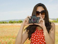 Young woman with camera in poppy field
